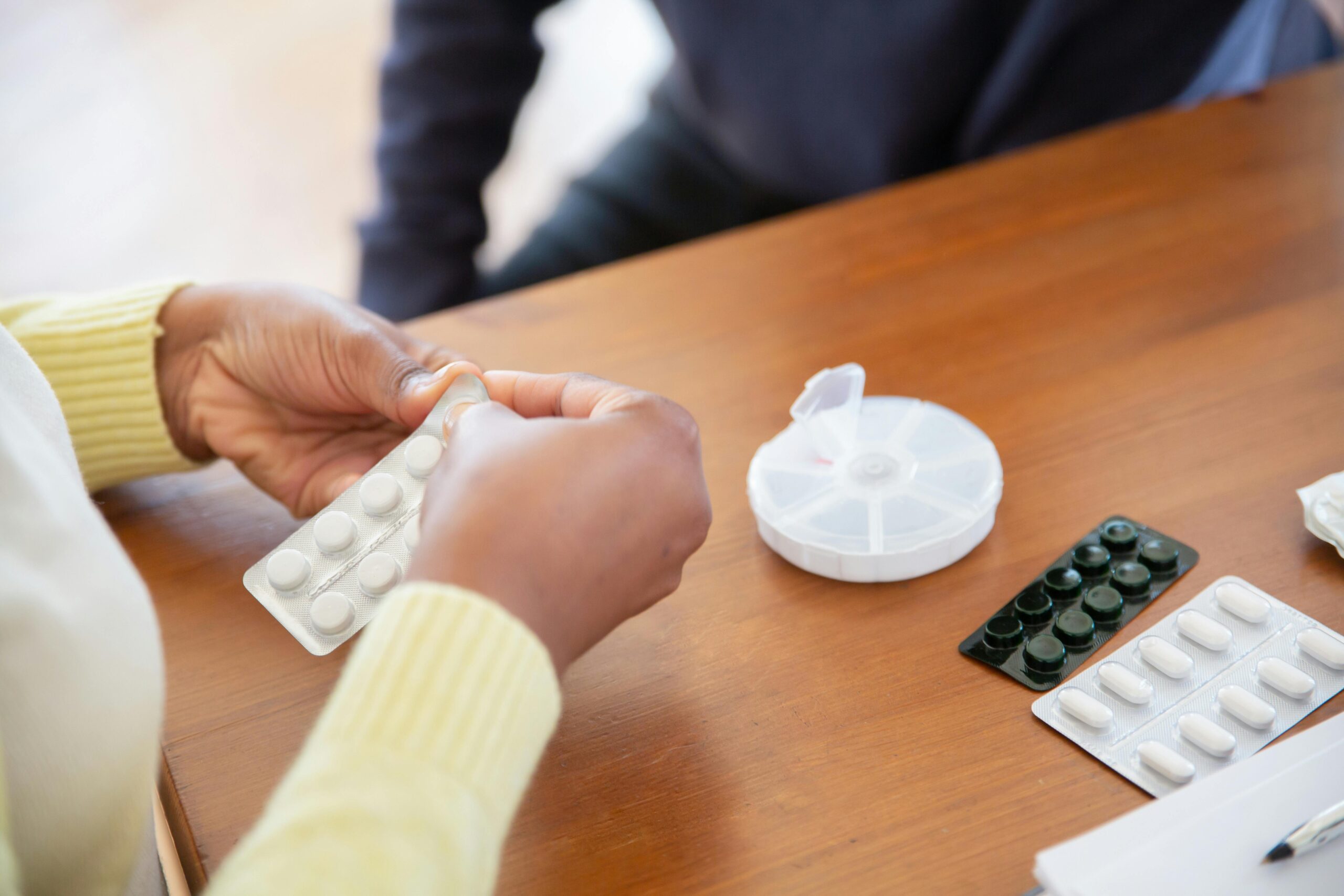 pexels-photo-7551663-7551663 Close-up of a nurse organizing pills and medications on a table in a care setting.